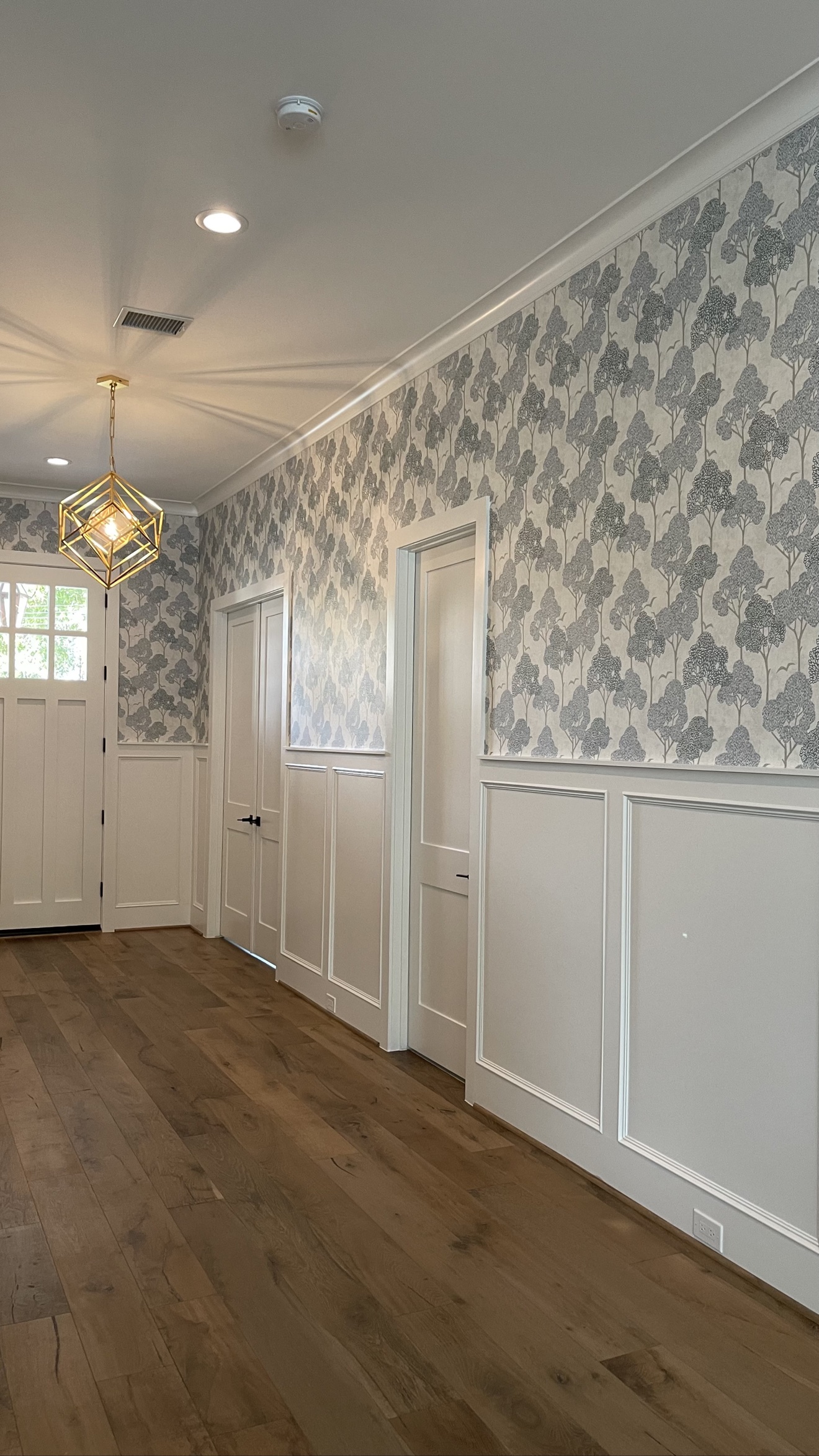 Gray tree-patterned wallpaper installed in an entryway