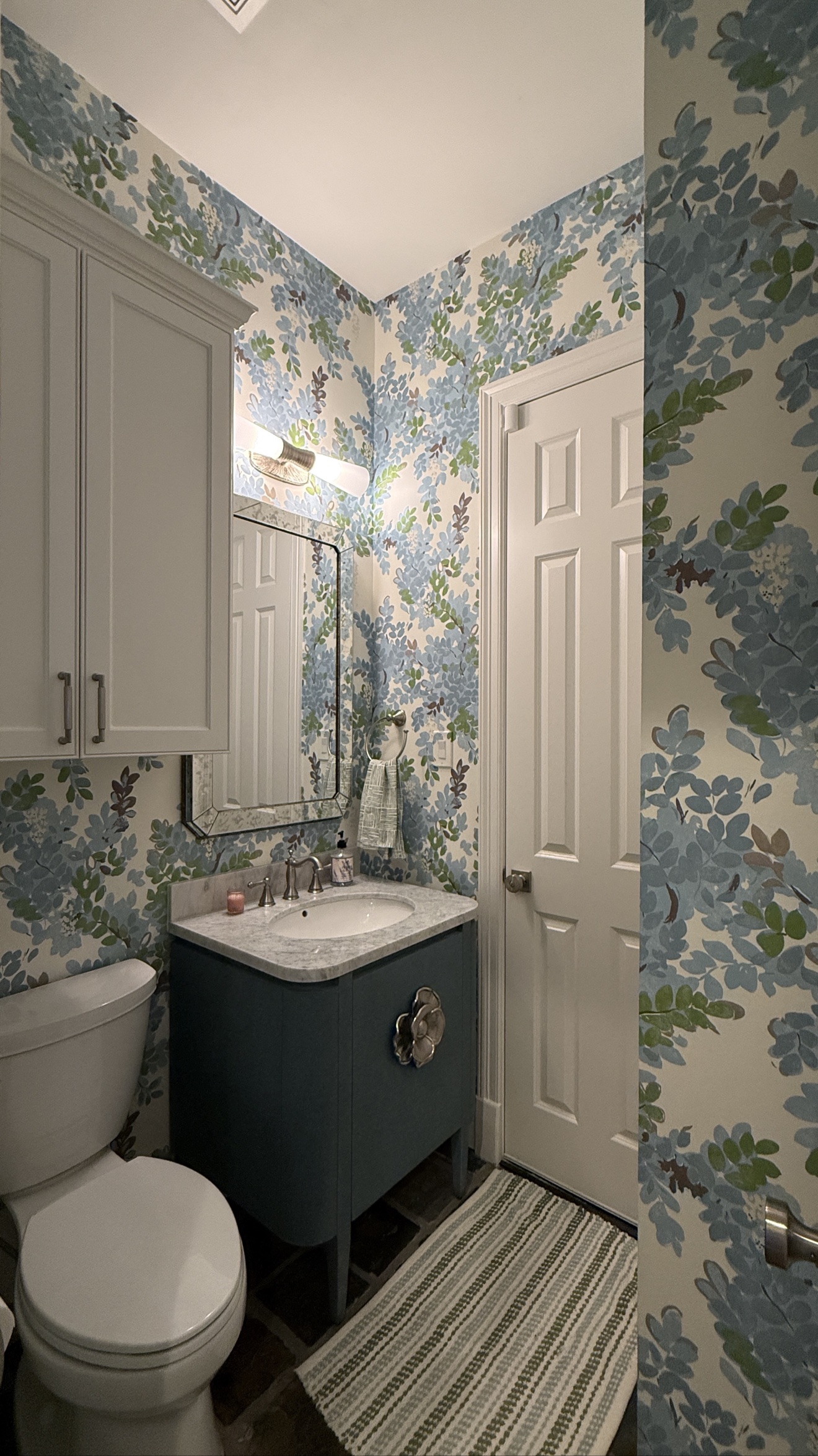 Blue floral wallpaper installed throughout a powder room