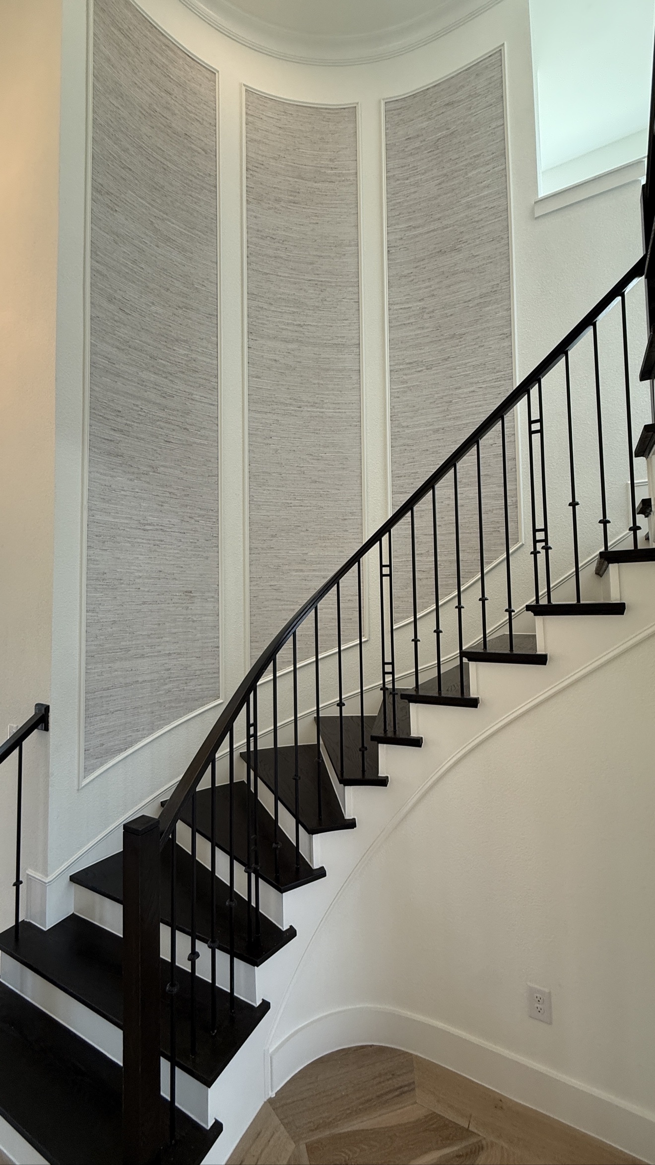 Textured grasscloth installed inside curved staircase wall panels