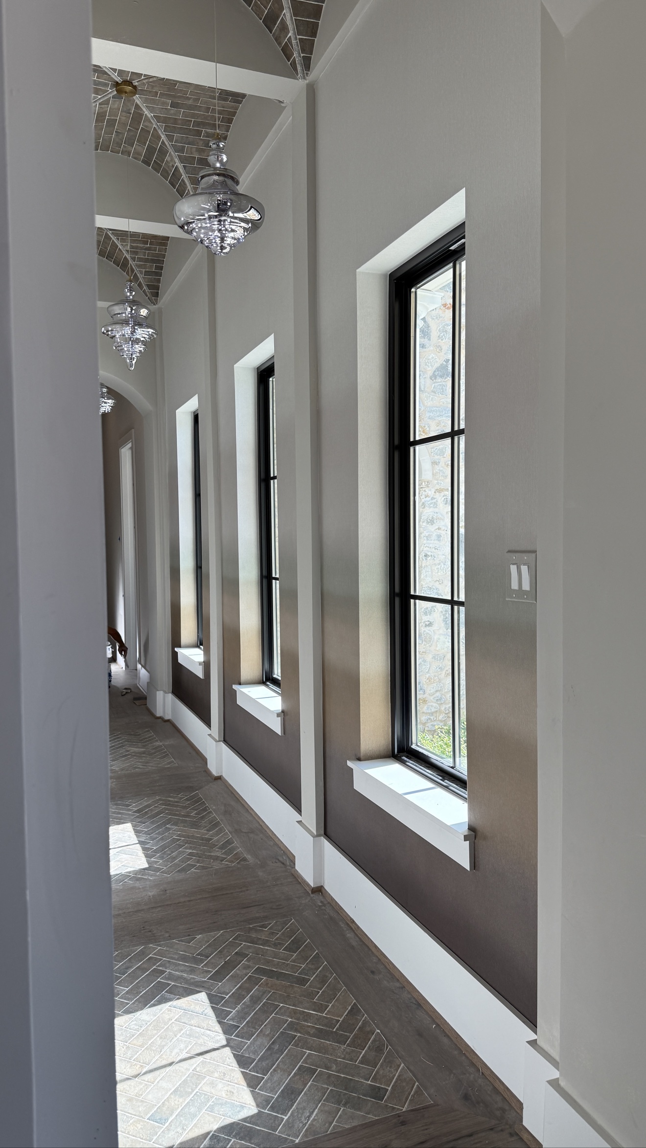 Neutral textured wallcovering installed along a tall windowed hallway