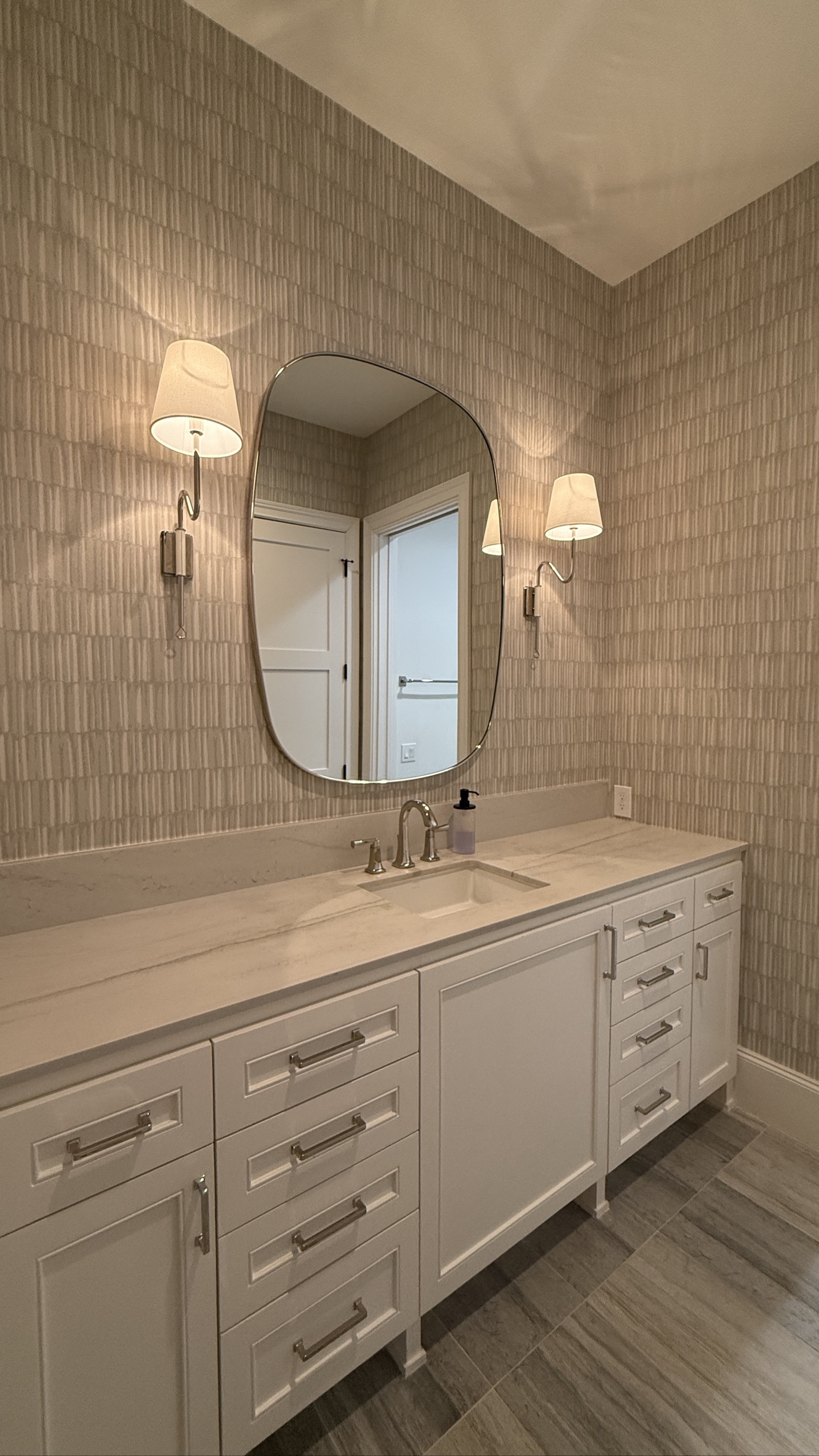 Neutral textured wallpaper installed around a bathroom vanity