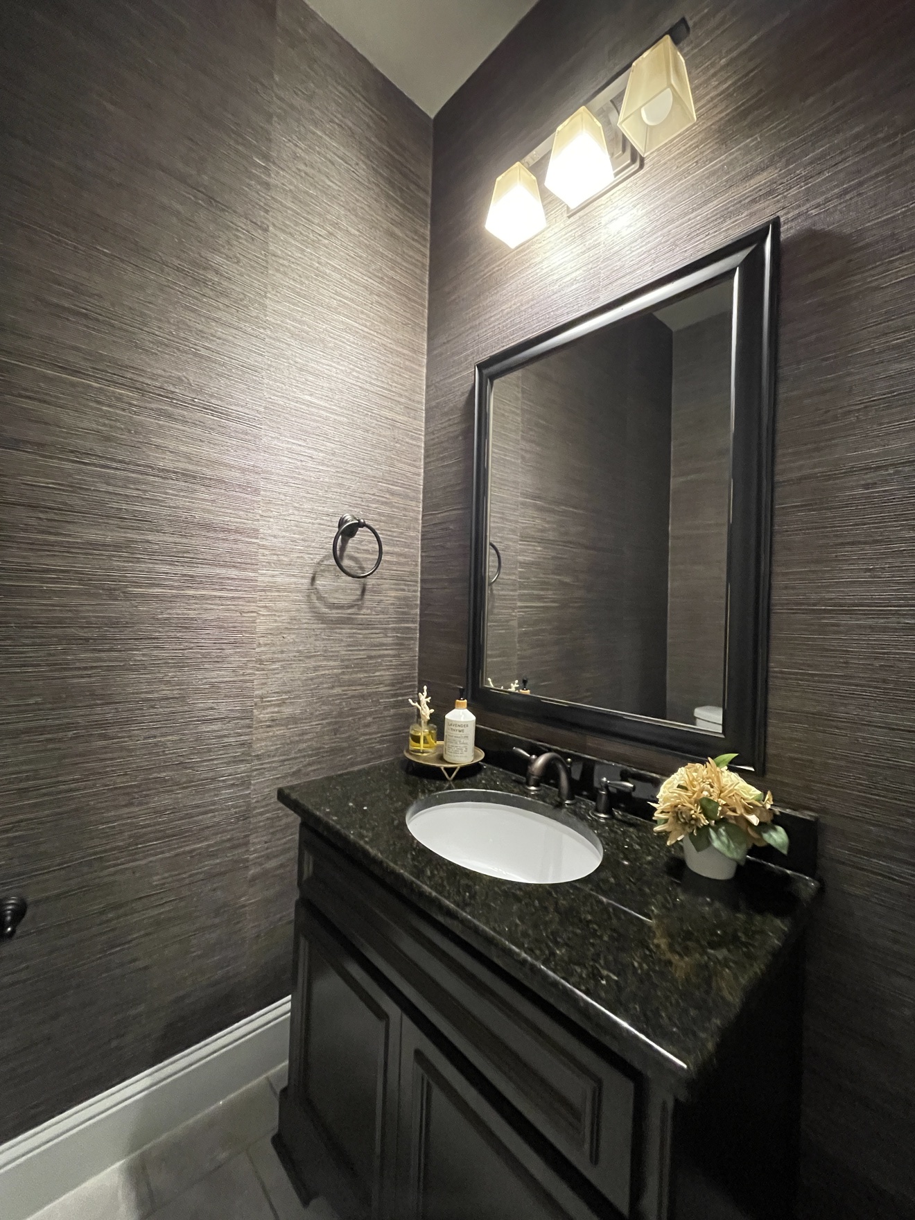 Dark textured grasscloth installed around a powder room vanity