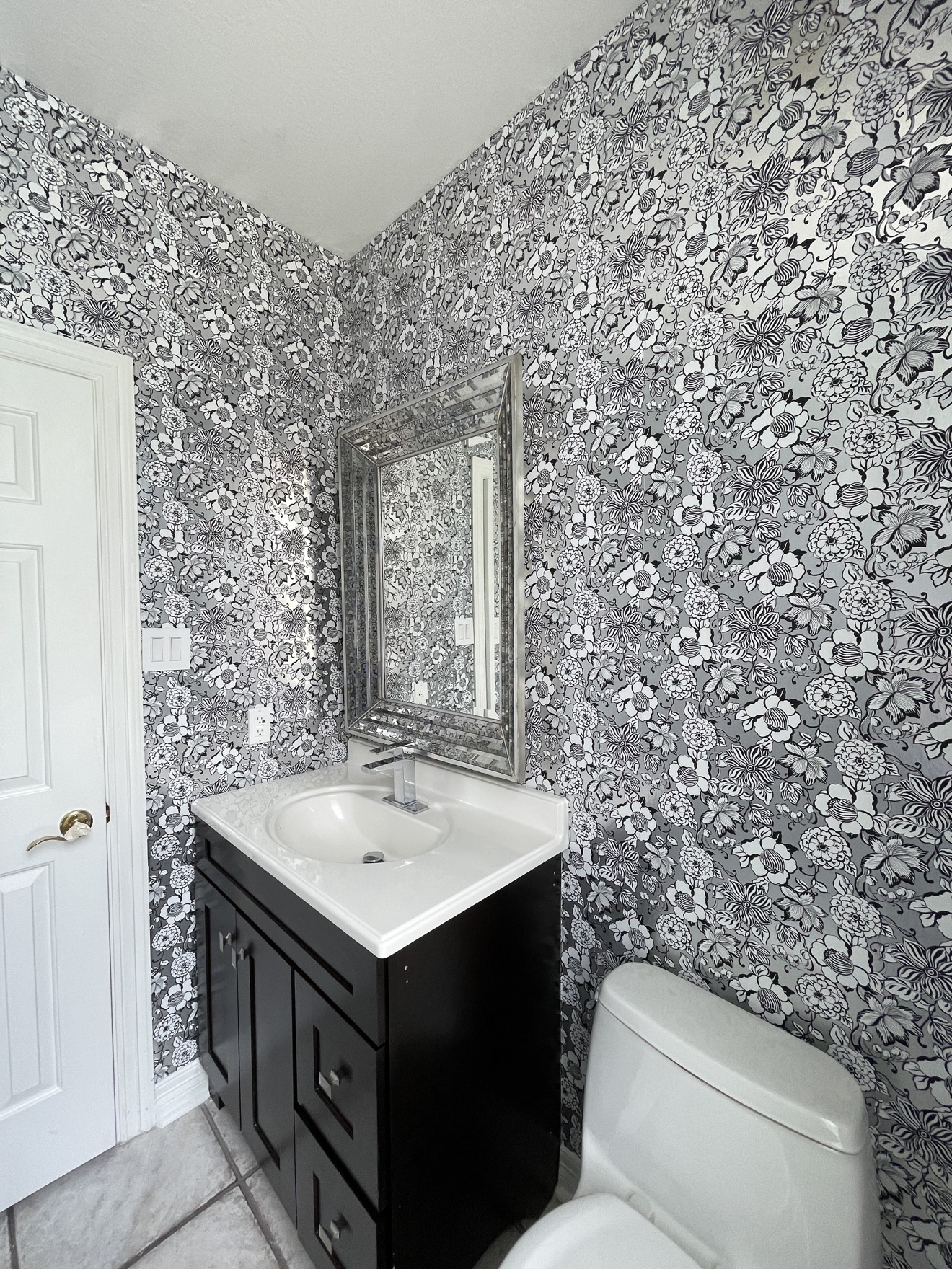 Black and white floral wallpaper installed in a bathroom