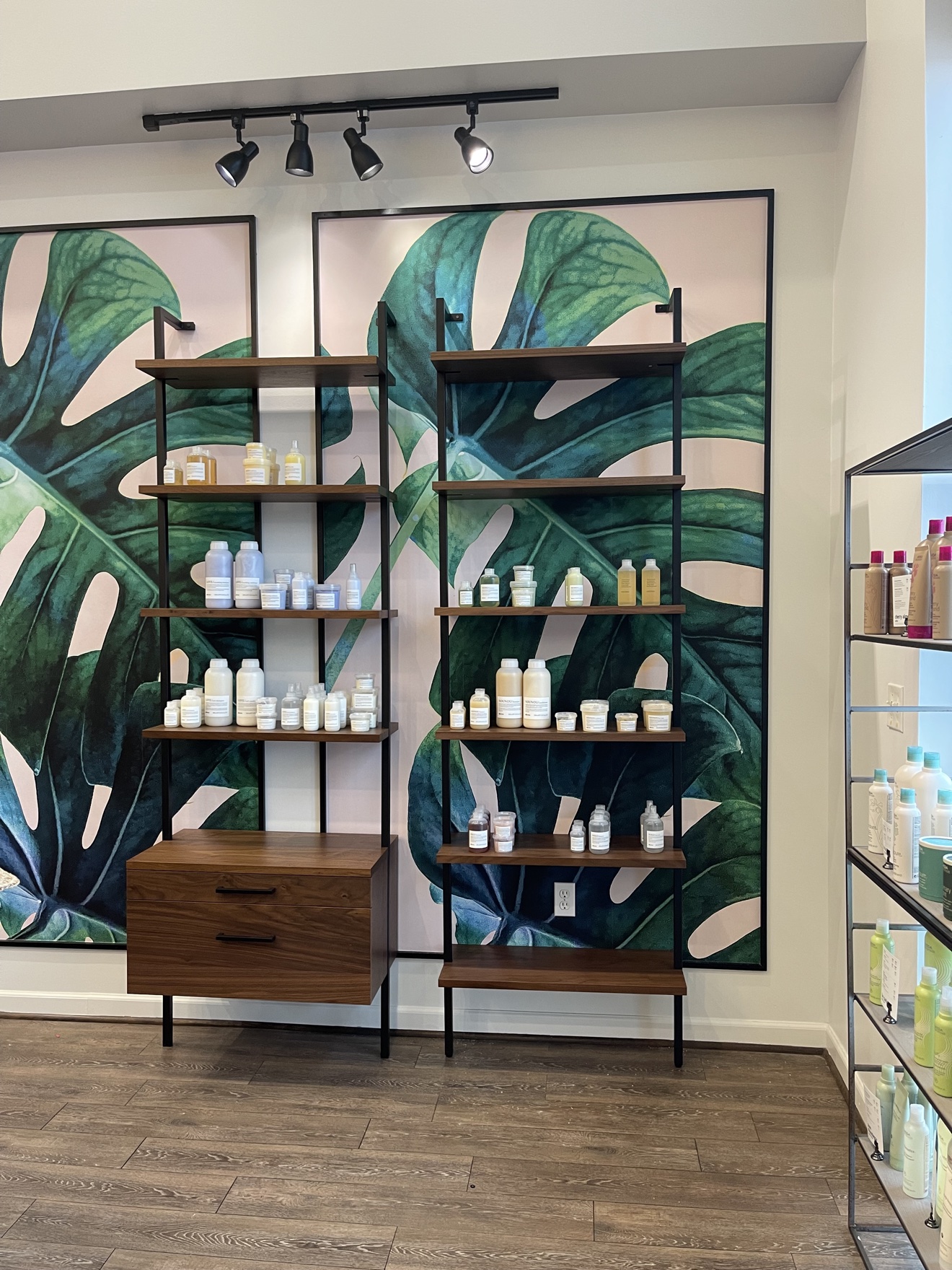 Large green botanical wallcovering panels installed behind retail shelving