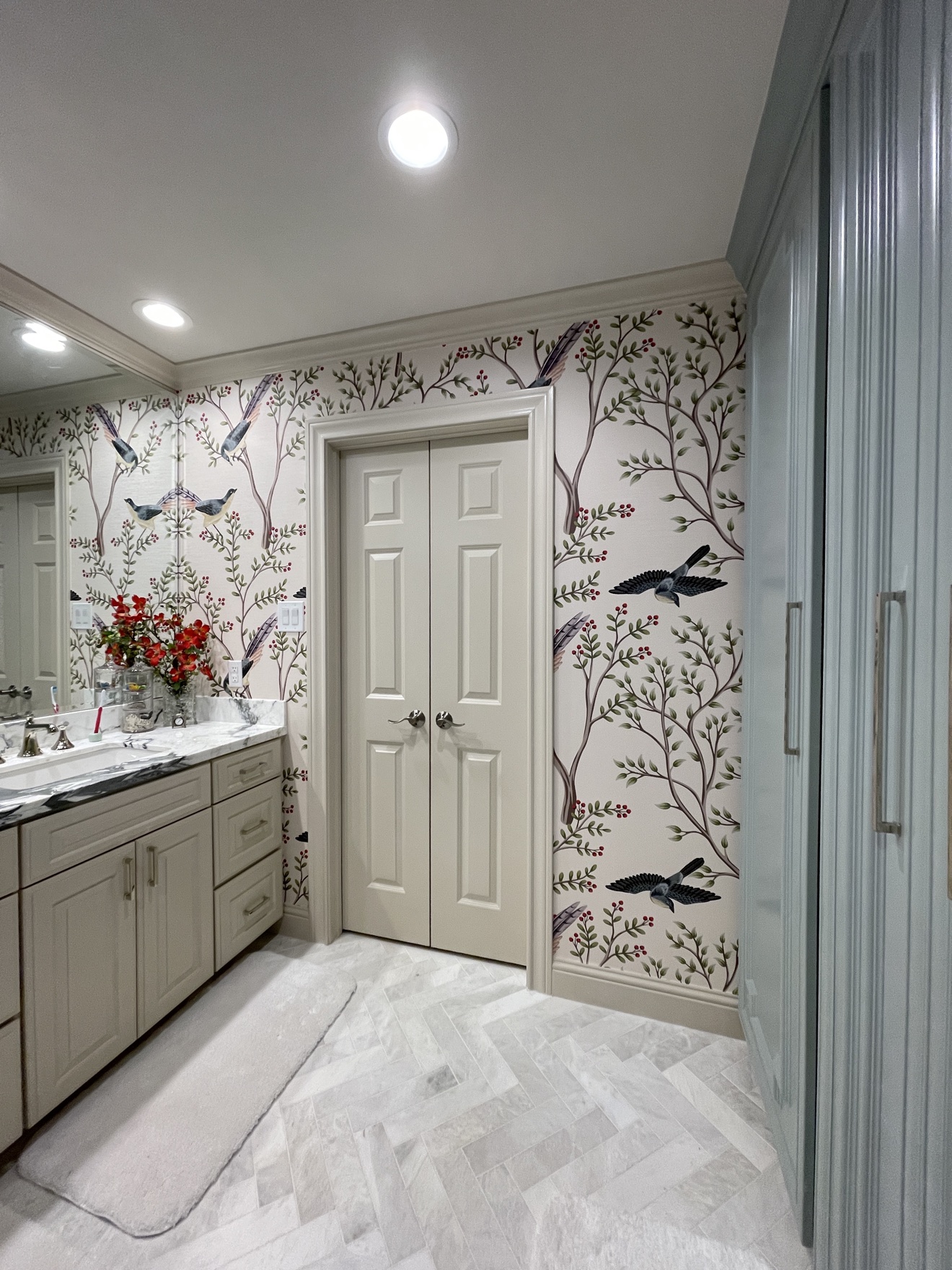 Bird and branch wallpaper installed around a finished bathroom vanity and mirror